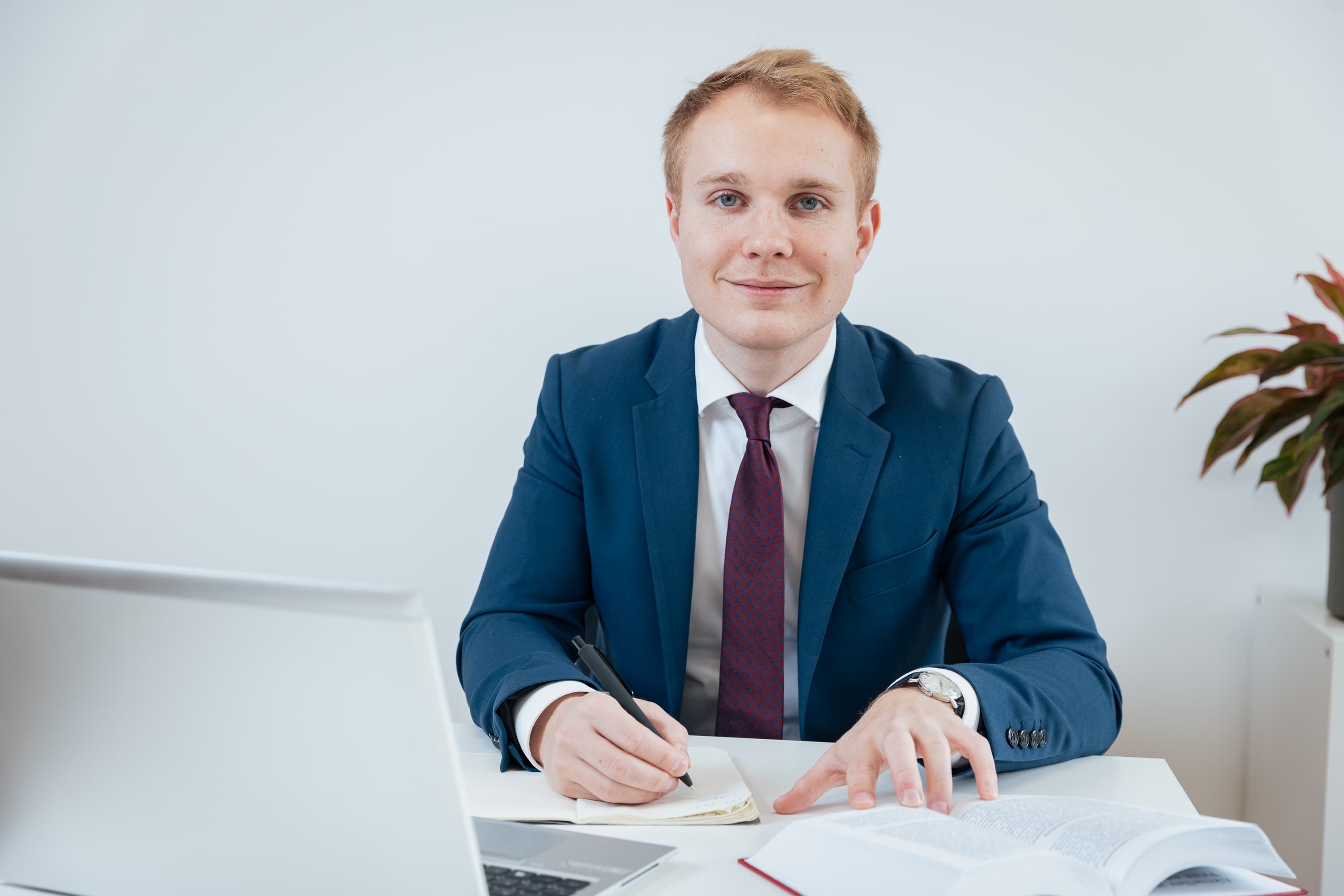 Mag. Erik de Buck - Rechtsanwalt am Schreibtisch mit Laptop und Gesetzbuch in seiner Kanzlei in Schwechat